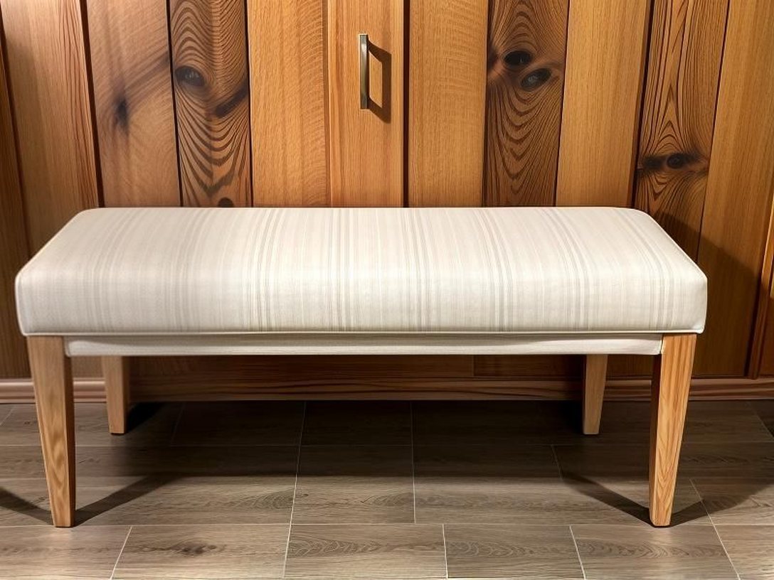 Banco de madera tapizado, junto a una pared de friso.
